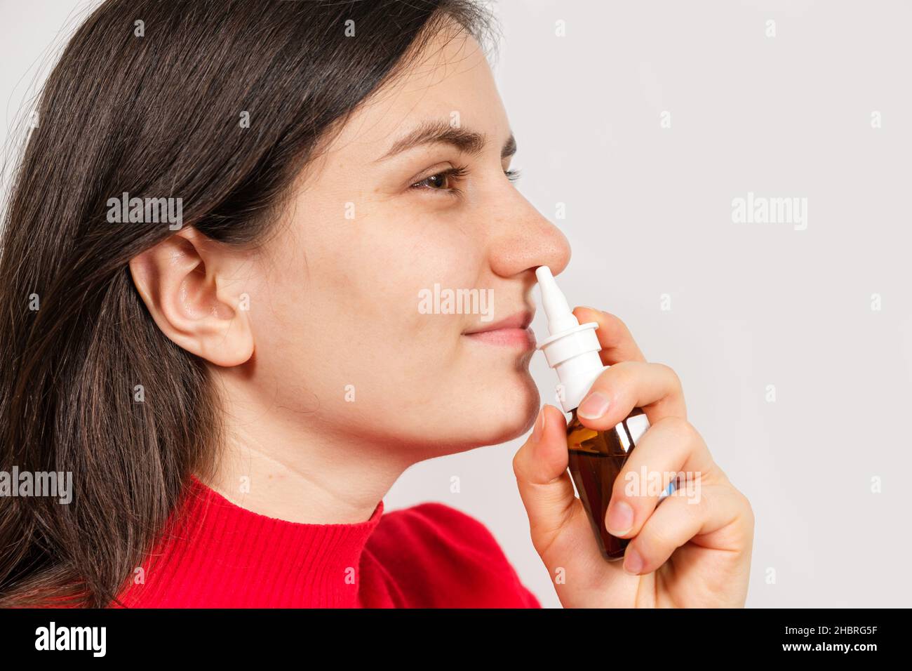 Eine Patientin schiebt ein Spray in die Nase, um Rhinitis, eine Allergie mit Atembeschwerden, zu behandeln. Textbereich kopieren. Stockfoto
