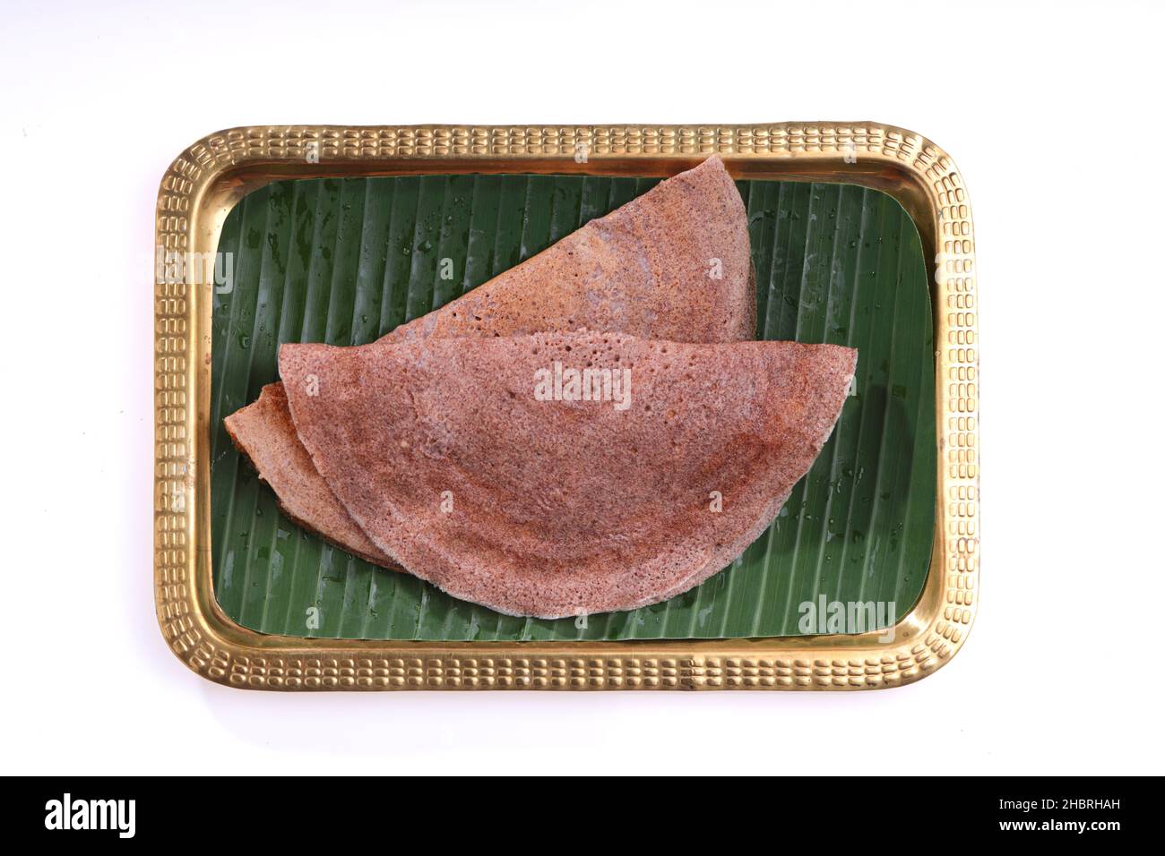 Ragi Dosa, gesundes südindisches Frühstückselement, das auf einem rechteckigen Messingteller mit Bananenblatt ausgekleidet ist. Stockfoto