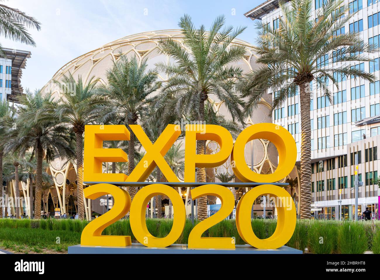 Dubai, VAE, 09.12.2021. Gelbes Logo der Expo 2020 auf der Expo 2020 Dubai mit Al Wasl Plaza und Palmen im Hintergrund. Stockfoto