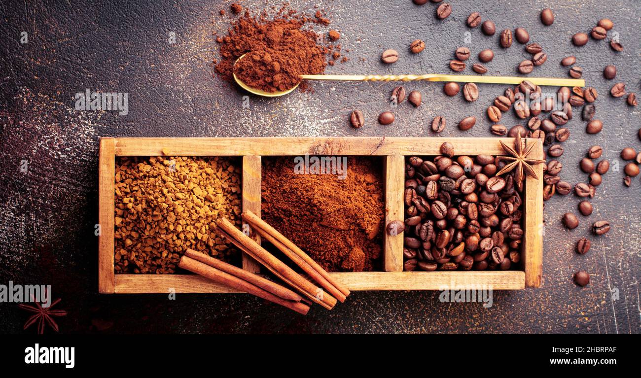 Food Hintergrund mit drei Arten von Kaffee: Bohnen, gemahlen, Instant in Holzkiste auf alten Beton braunen Hintergrund. Rustikaler Stil. Selektiver Fokus. Oben Stockfoto