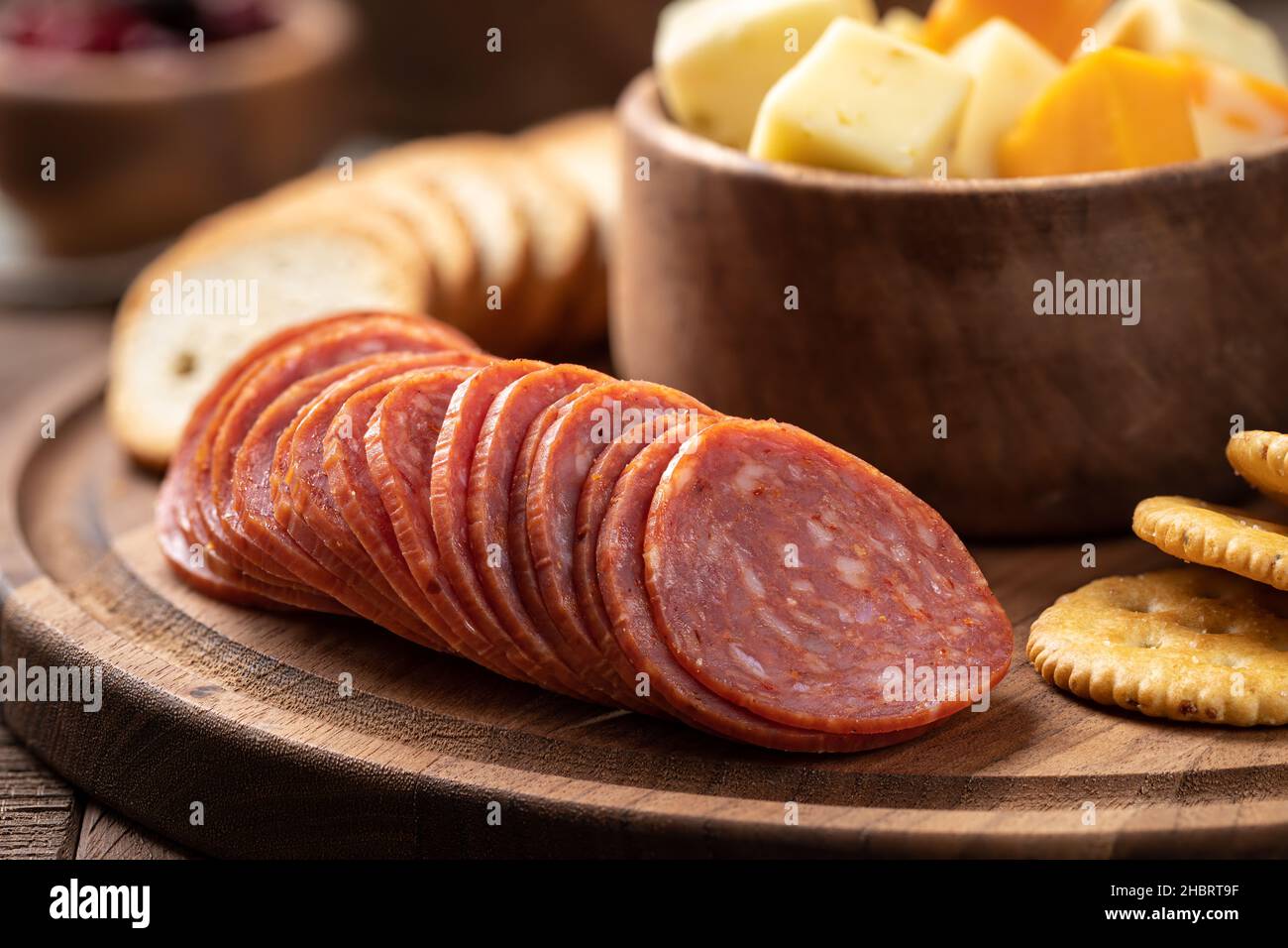 Snack-Platte mit in Scheiben geschnittenen Salami, Knabberbröcken, gerösteten Runden und Käsewürfeln in einer Schüssel in der Nähe Stockfoto