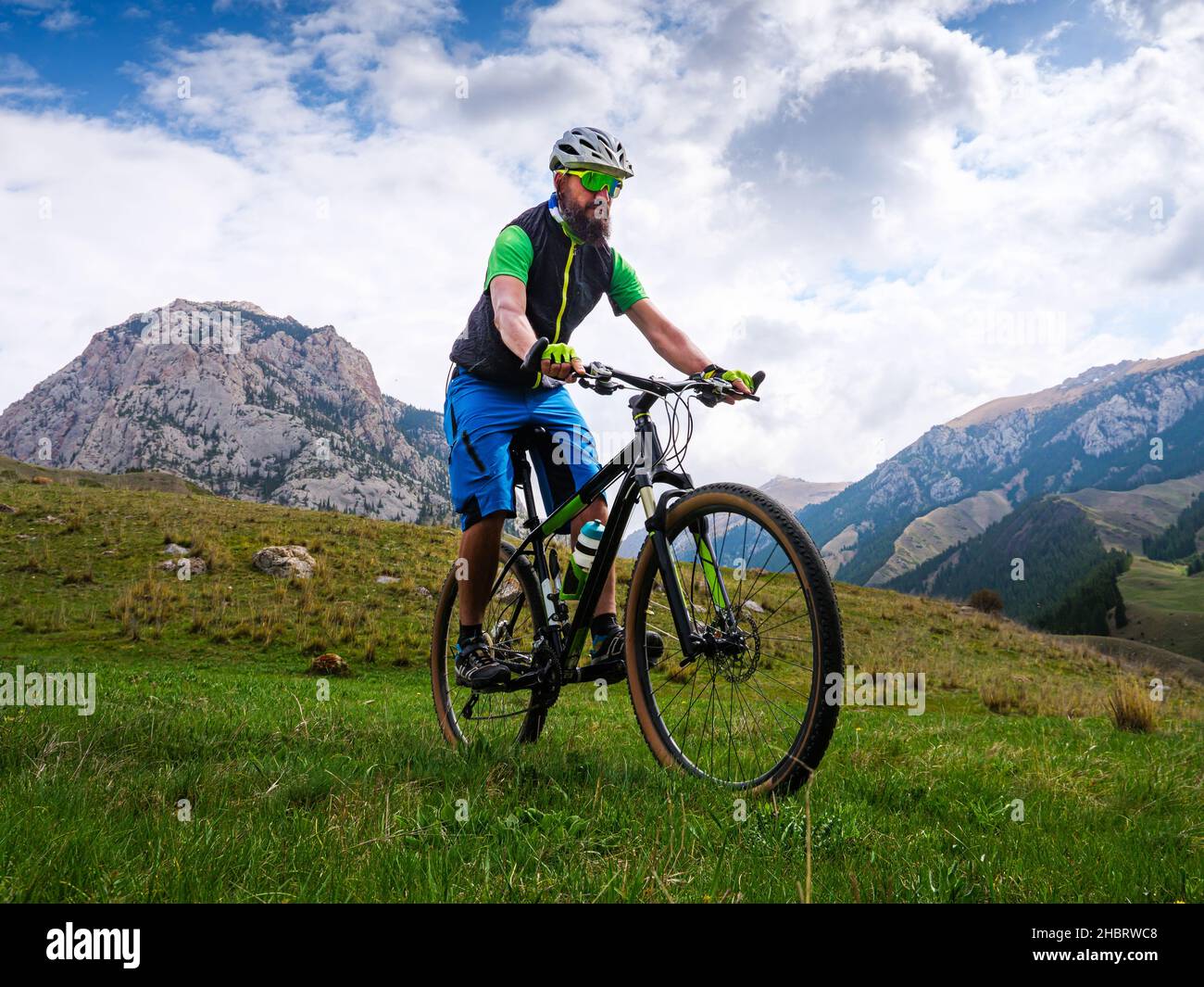 Der Radfahrer fährt an einem Sommertag in den Bergen. Bärtiger Sportler auf einem Mountainbike. Aktivitäten im Freien Stockfoto