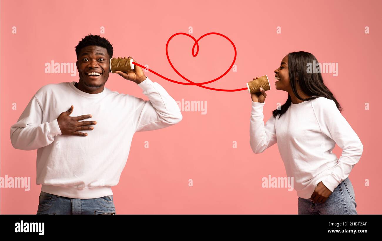 Glückliche afroamerikanische Liebhaber, die sich durch Zinn unterhalten, können telefonieren Stockfoto