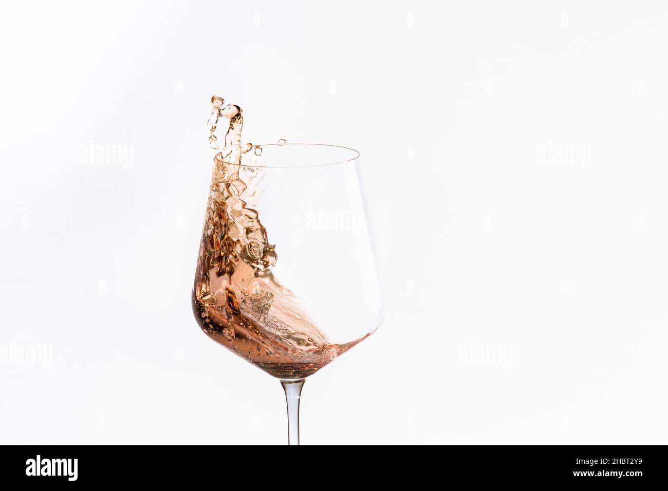 Ein Glas spritzendem Alkohol auf einem hellen Hintergrund Stockfoto
