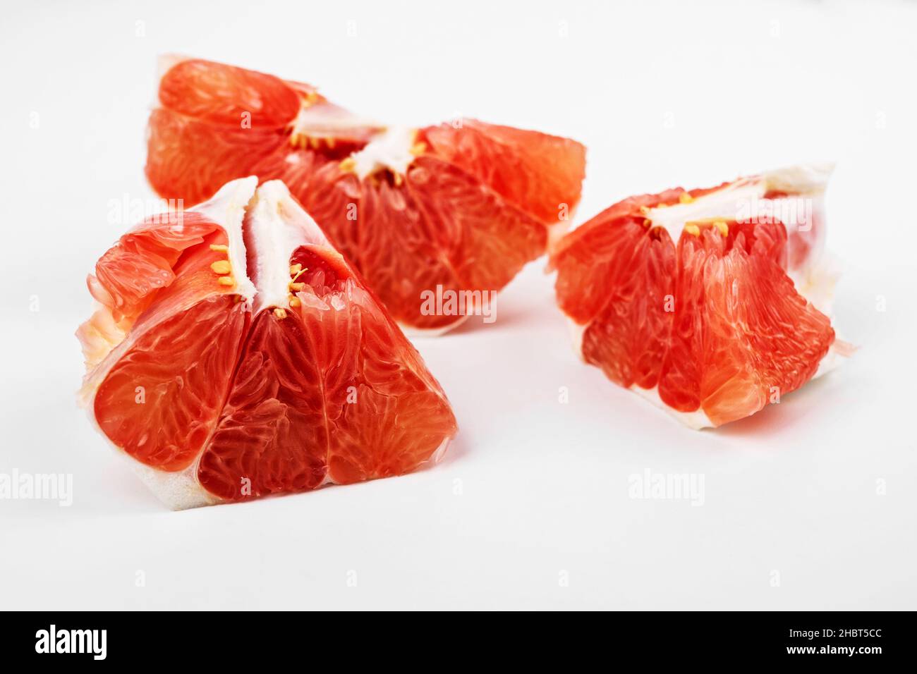 Stück süße rote Grapefruit, schöne Struktur und Textur von Fruchtfleisch. Nahaufnahme auf weißem Hintergrund. Stockfoto