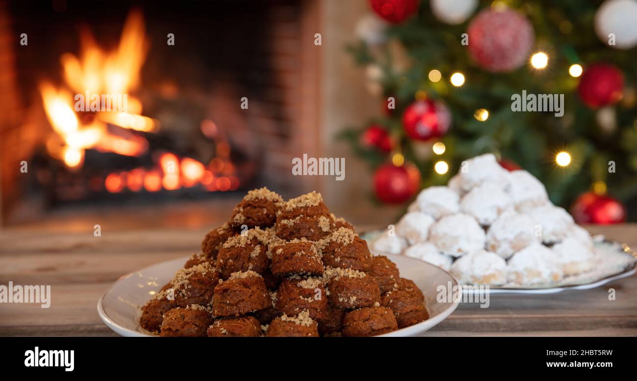 Weihnachten griechischen melomakarona und kourabiedes, brennenden Kamin und Weihnachtsbaum Hintergrund. Traditionelle hausgemachte Desserts. Stockfoto