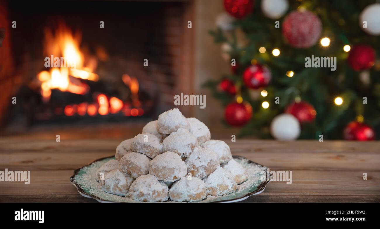Weihnachten griechische Kourabiedes, brennender Kamin und Weihnachtsbaum Hintergrund. Traditionelle hausgemachte Desserts. Stockfoto