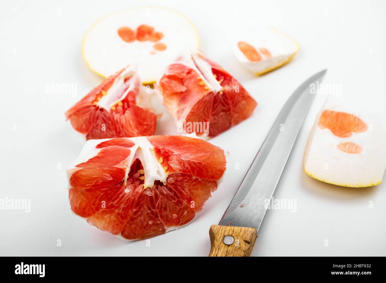 Stücke und Schale von roter Grapefruit, schöne Textur und Struktur von Fruchtfleisch, Messer auf weißem Hintergrund, Nahaufnahme. Stockfoto