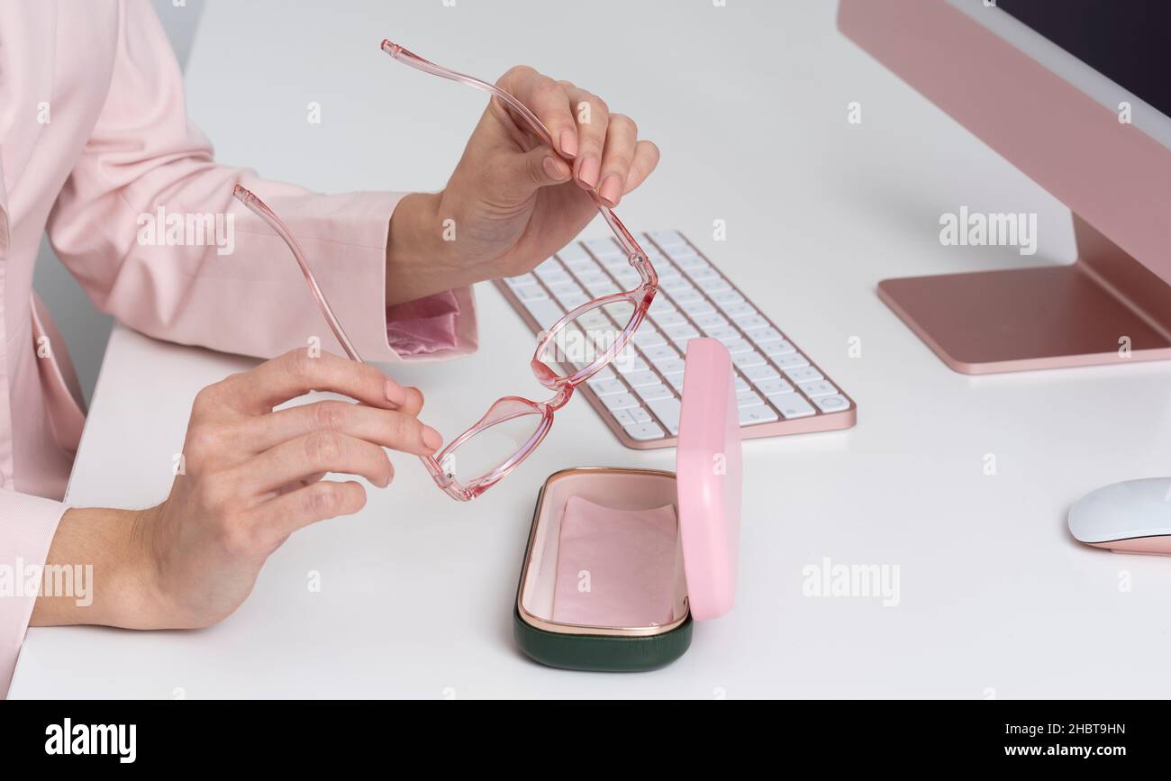 Salisbury, England, Großbritannien. 2021. Womans Hände entfernen Brille aus dem Fall mit Rückfall von Computer und Tastatur. Stockfoto