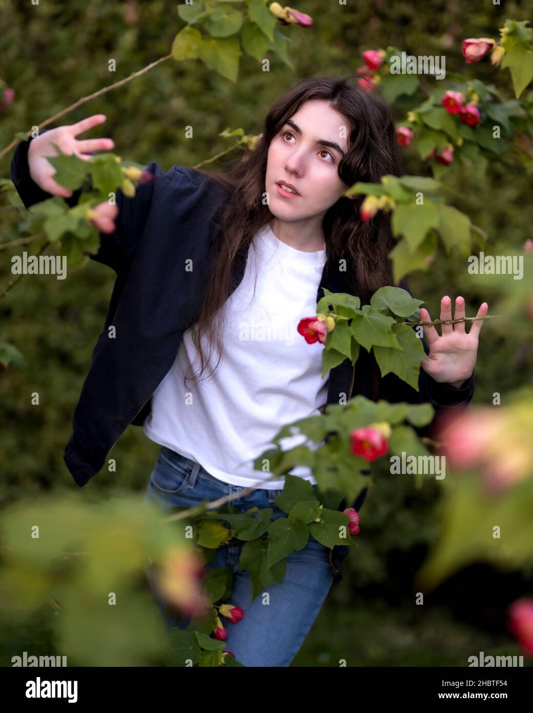 Teenager-Frau, die ein Blumenbett erkundet Stockfoto