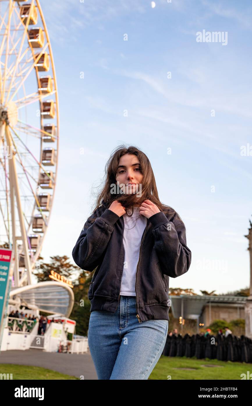 Junge Frau, die vor dem Riesenrad steht Stockfoto