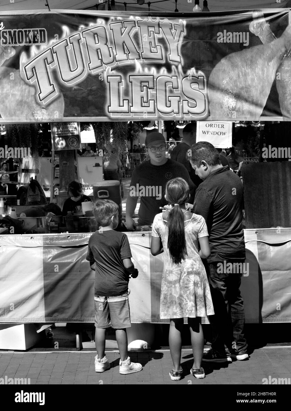 Ein Vater kauft geräucherte putenbeine für zwei Kinder von einem Lebensmittelhändler bei einem Outdoor-Festival in Santa Fe, New Mexico. Stockfoto