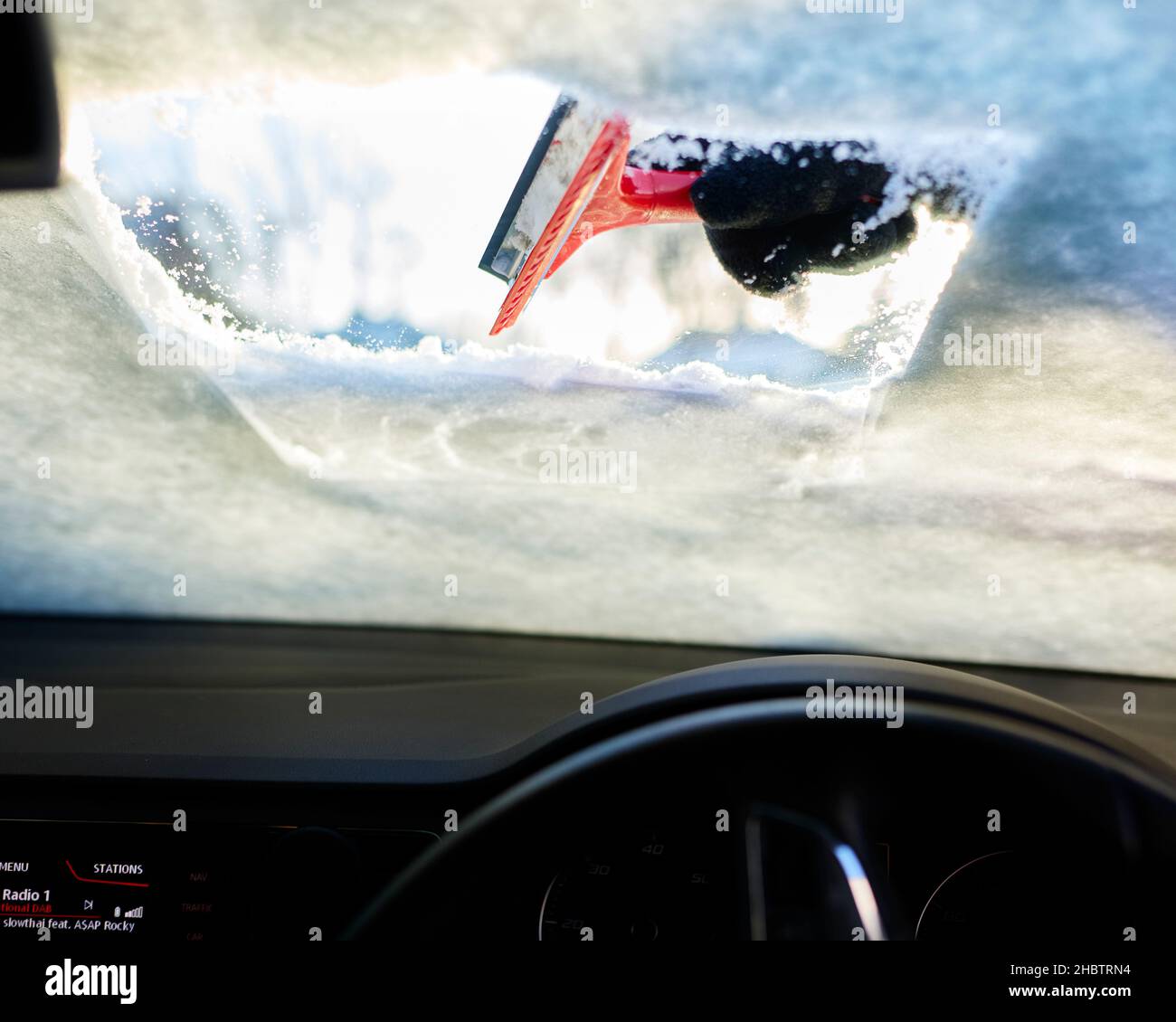 Fahrer räumt Schnee von der Windschutzscheibe Stockfoto