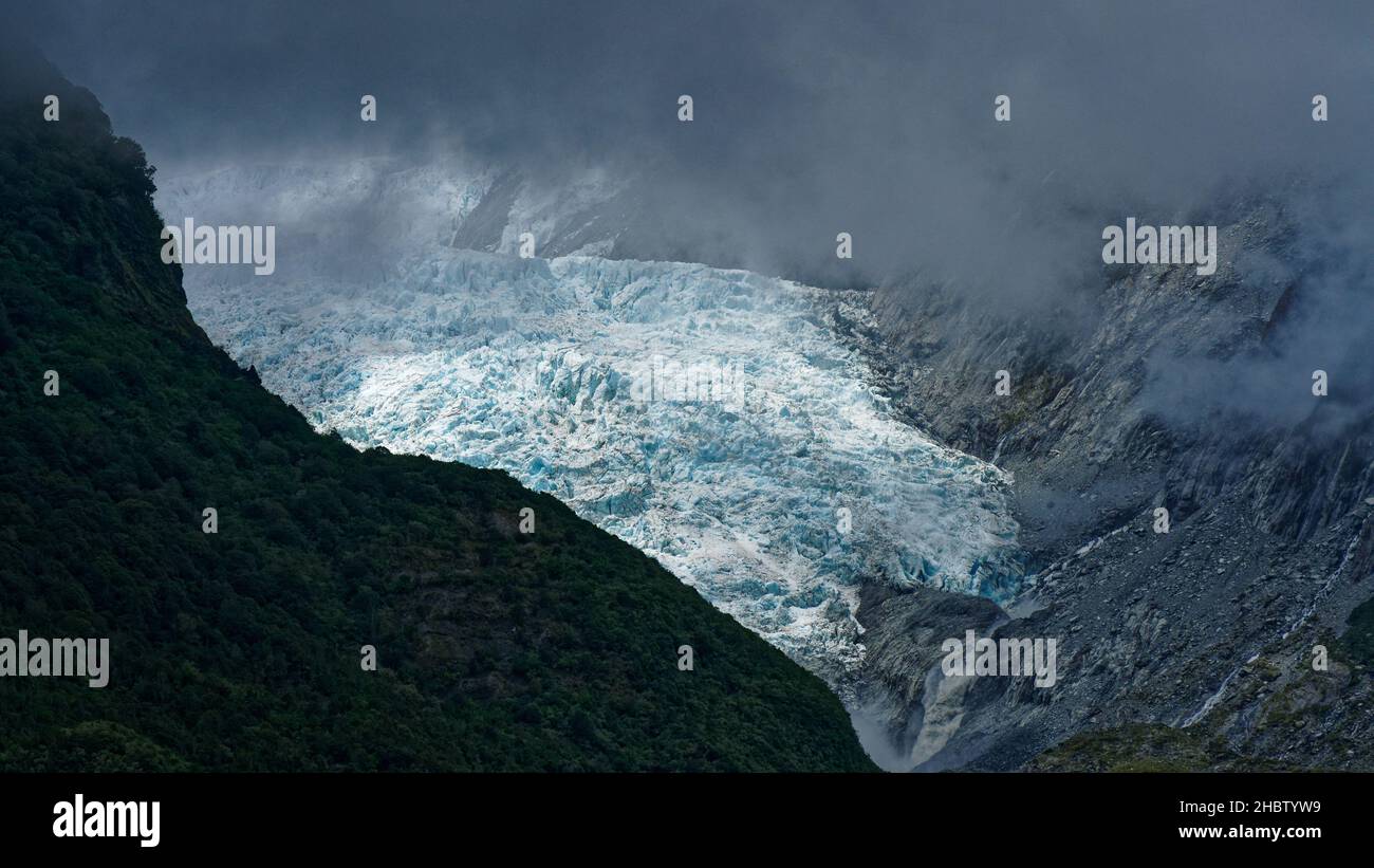 Franz Josef Gletscher unter stürmischem Himmel, Westland Tai Poutini Nationalpark Südinsel, Westküste, Neuseeland. Schmelzwasser, das ins Tal fließt Stockfoto
