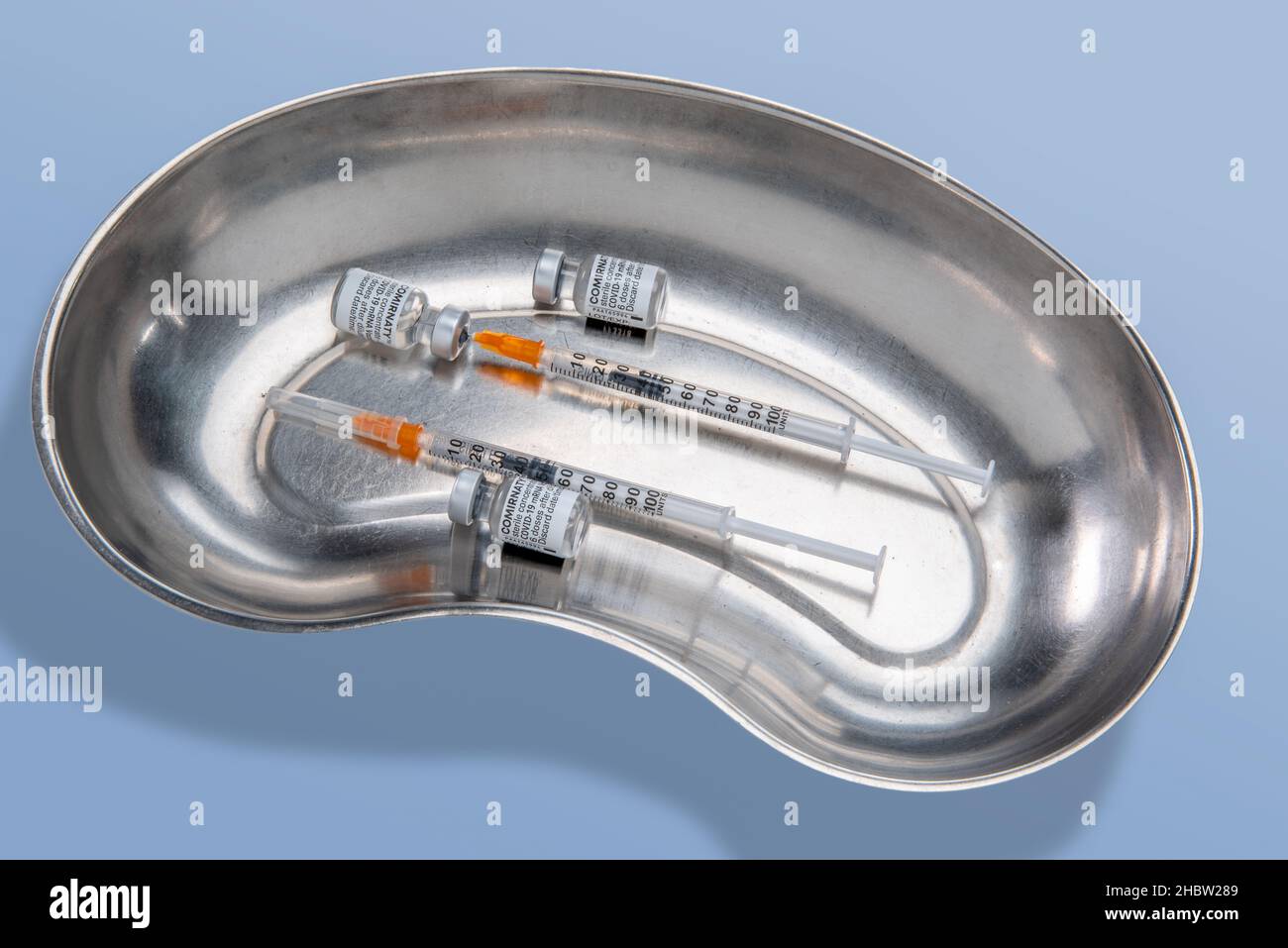 Turin, Italien - 21. Dezember 2021: Pfizer-BioNTech COVID-19-Impfstoff Comirnaty-Fläschchen, drei Fläschchen mit Spritze, die Impfstoffdosis in rostfreiem Medi ansaugt Stockfoto