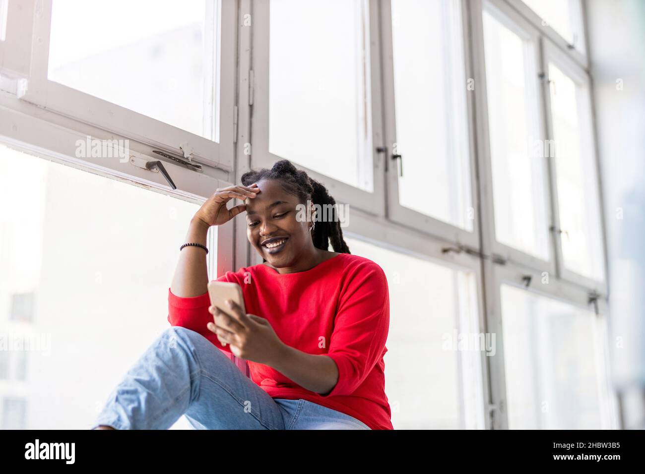 Junge Frau mit Smartphone im Loft-Büro Stockfoto