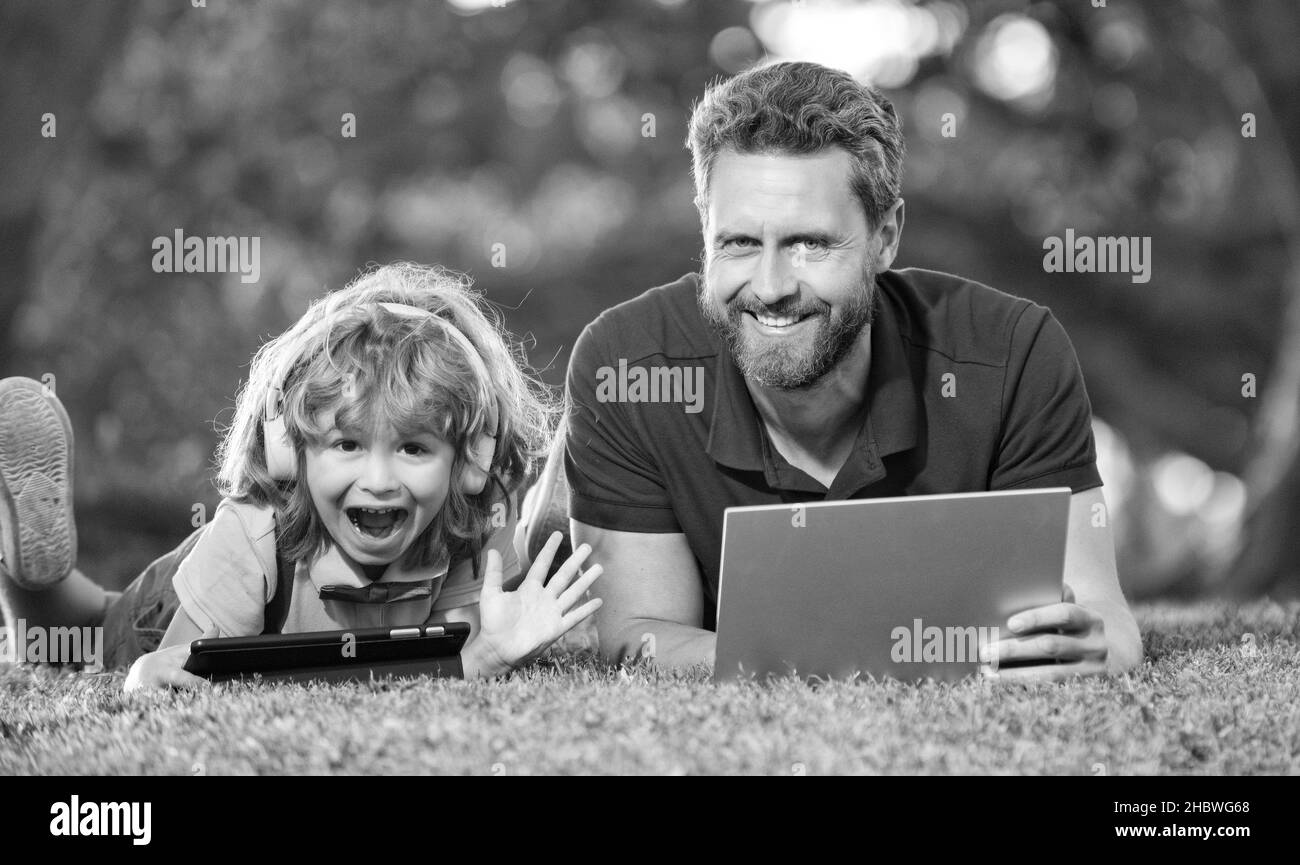 Vater und Sohn nutzen moderne Kommunikationstechnik im Park. Familienblogging Stockfoto