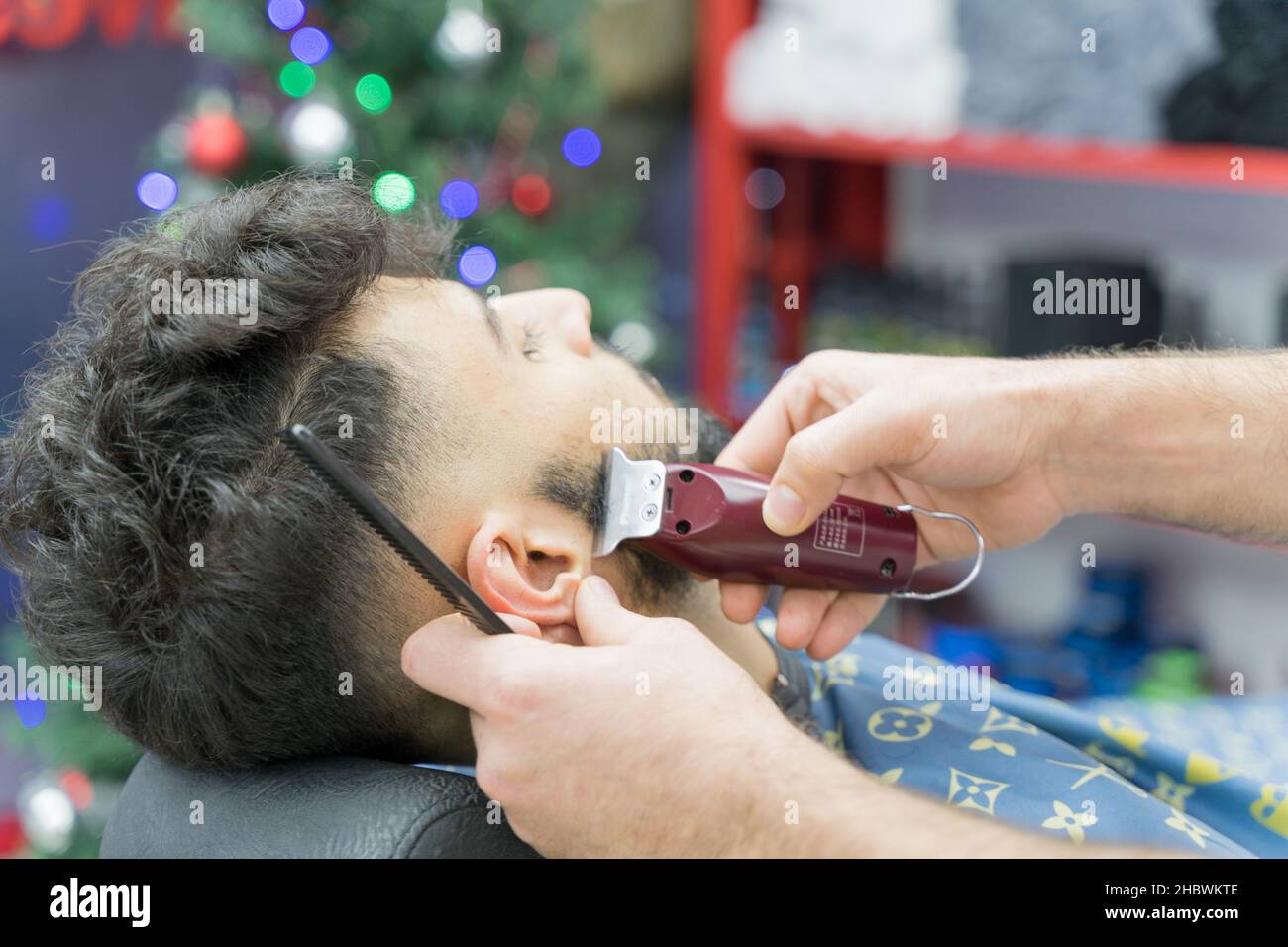 Ein Barbier schneidet im Friseurladen London England mit einem Haarschneider die Seitenbrands eines Gentleman Stockfoto