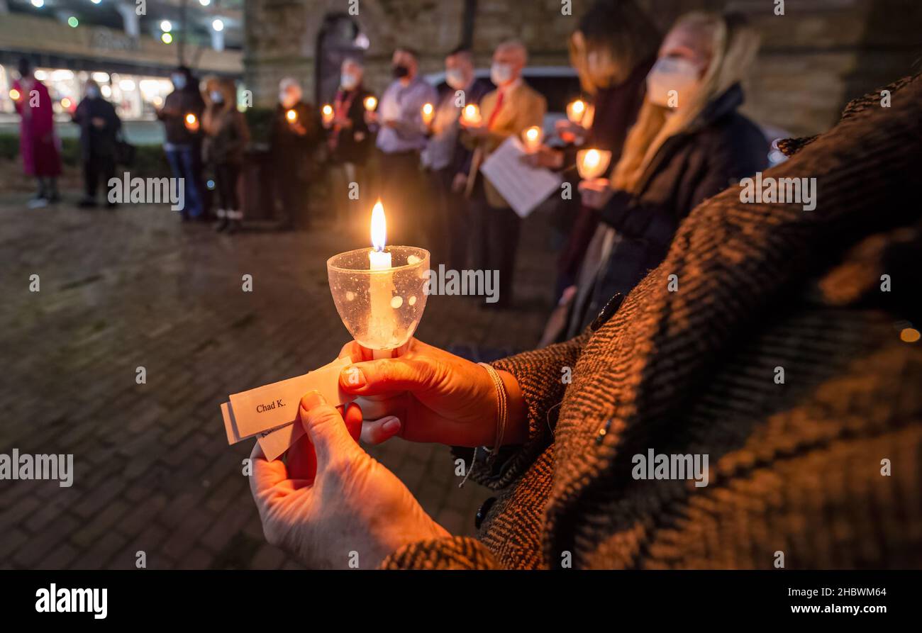 Wilkes Barre, Usa. 21st Dez 2021. Eine Frau trägt die Namen von zwei Obdachlosen, die in der Gemeinde während einer Mahnwache in der längsten Nacht des Jahres gestorben sind. In der längsten Nacht, der Wintersonnenwende, wenn der Tag am kürzesten ist, werden sich Gemeinden versammeln und eine Mahnwache abhalten, um an Obdachlose zu erinnern, die auf der Straße gestorben sind. Die St.-Stephans-Kirche in Wilkes-Barre hielt die Mahnwache für das Jahr 20th und fügte 6 neue Namen für das Jahr 2021 hinzu. Kredit: SOPA Images Limited/Alamy Live Nachrichten Stockfoto