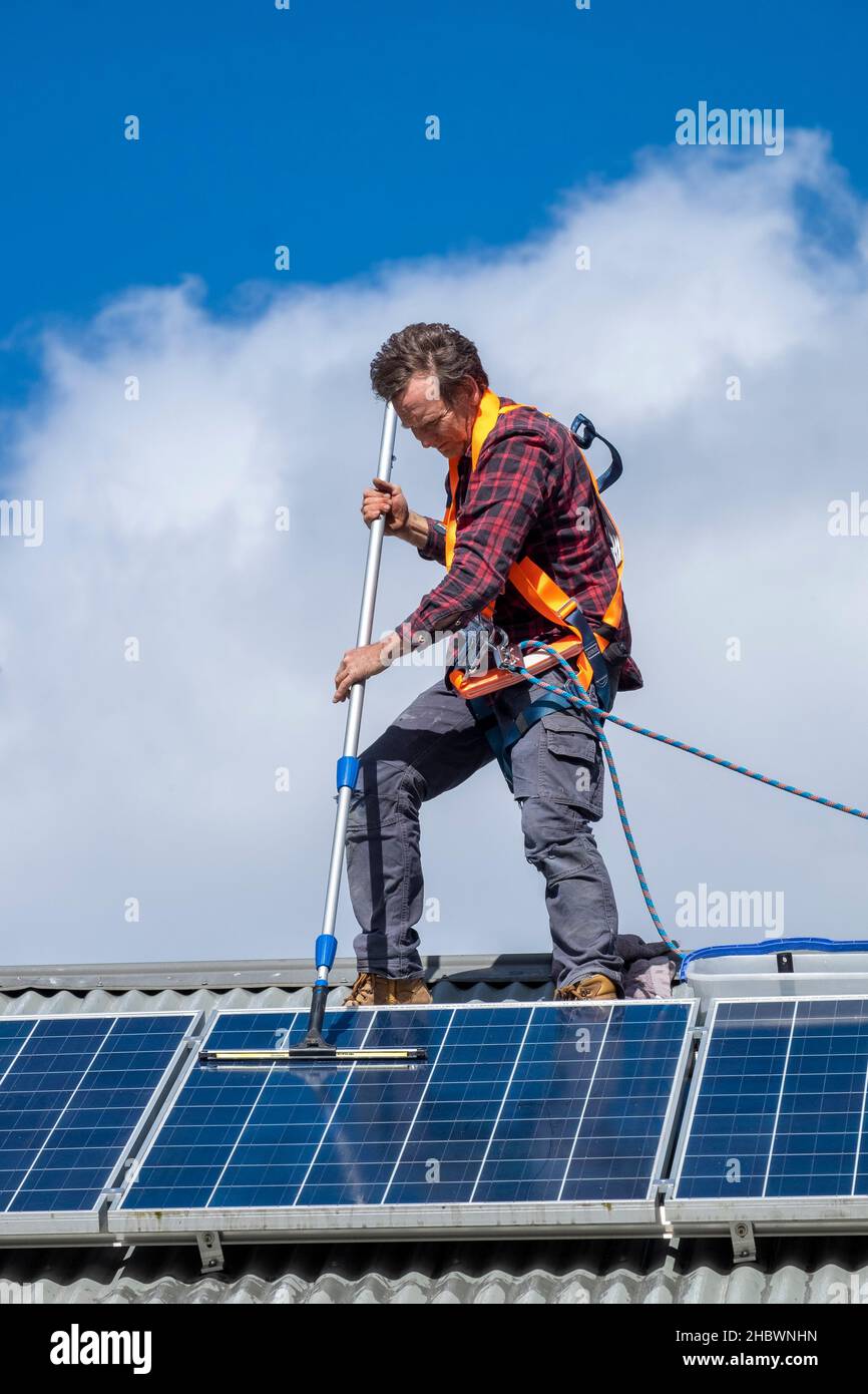 Handwerker, der Solarpaneele auf dem Dach des Hauses reinigt Stockfoto