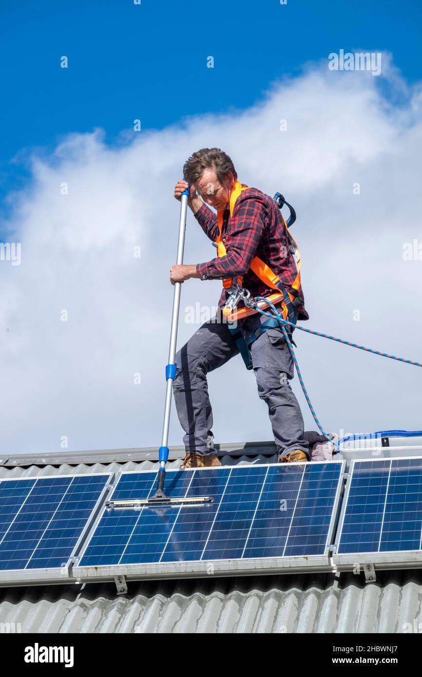 Handwerker, der Solarpaneele auf dem Dach des Hauses reinigt Stockfoto