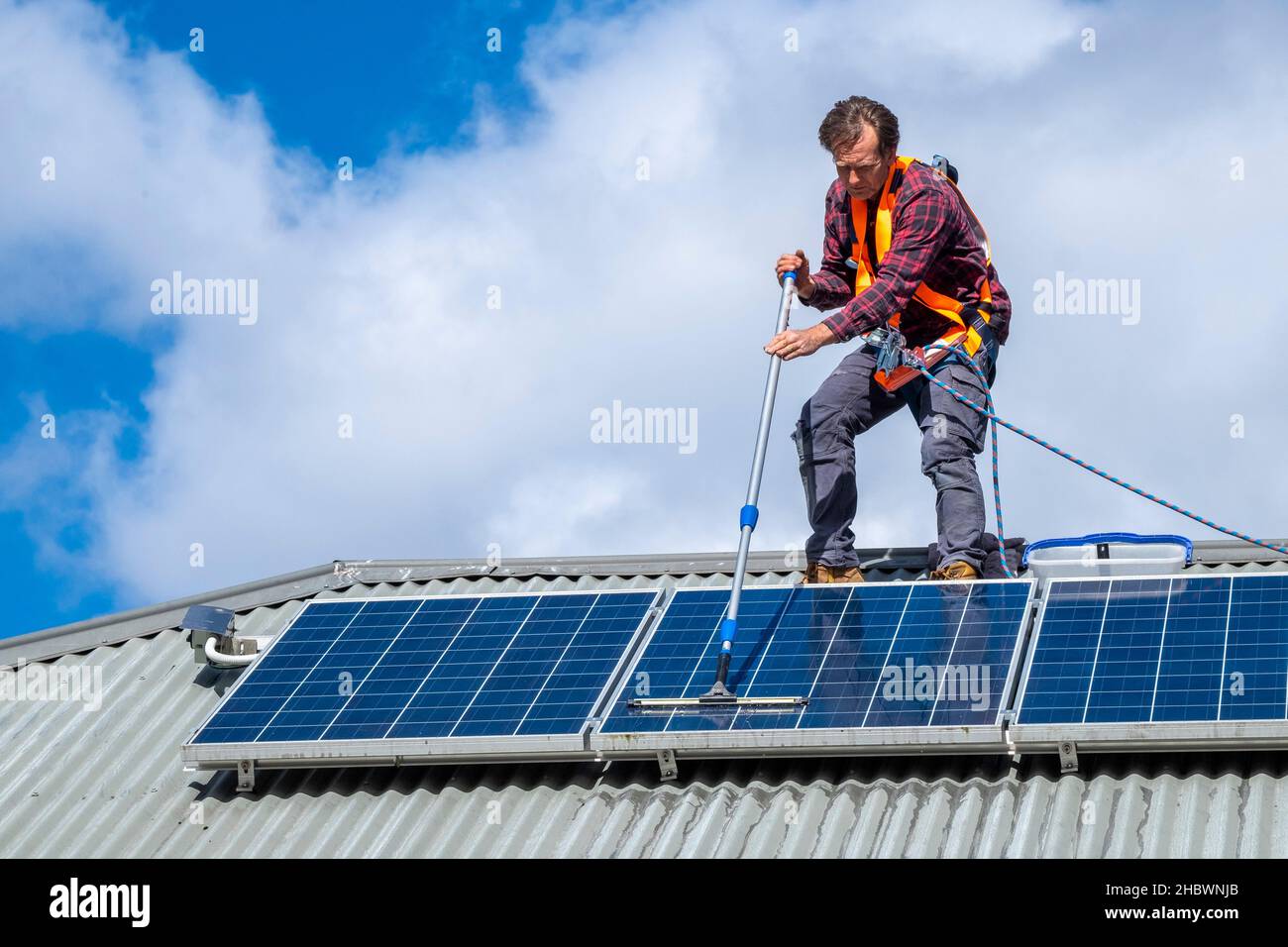 Handwerker, der Solarpaneele auf dem Dach des Hauses reinigt Stockfoto
