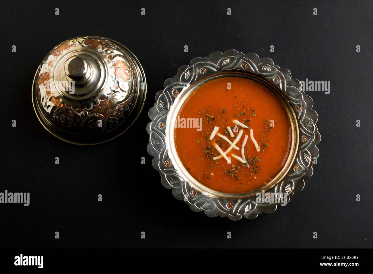 Traditionelle türkische Tomatensuppe in der stilvollen Vintage-Kupfersuppe.Käse- und Minzgarnierung.Draufsicht, schwarze Oberfläche. Stockfoto