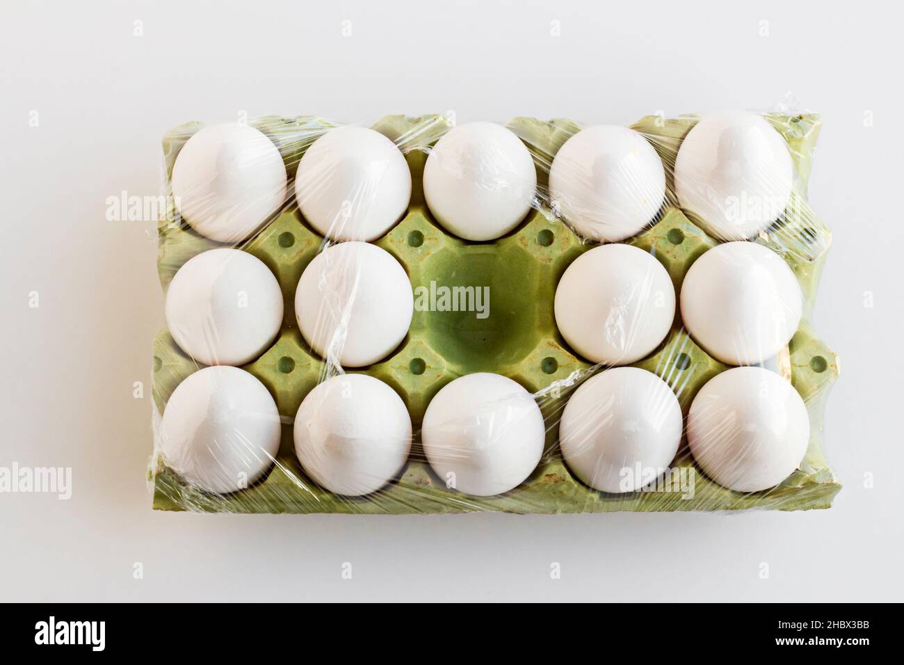 Frische, organische weiße Farbe, fünfzehn Eier auf Karton, in Stretchfolie gewickelt und ein Platz ist leer. Stockfoto
