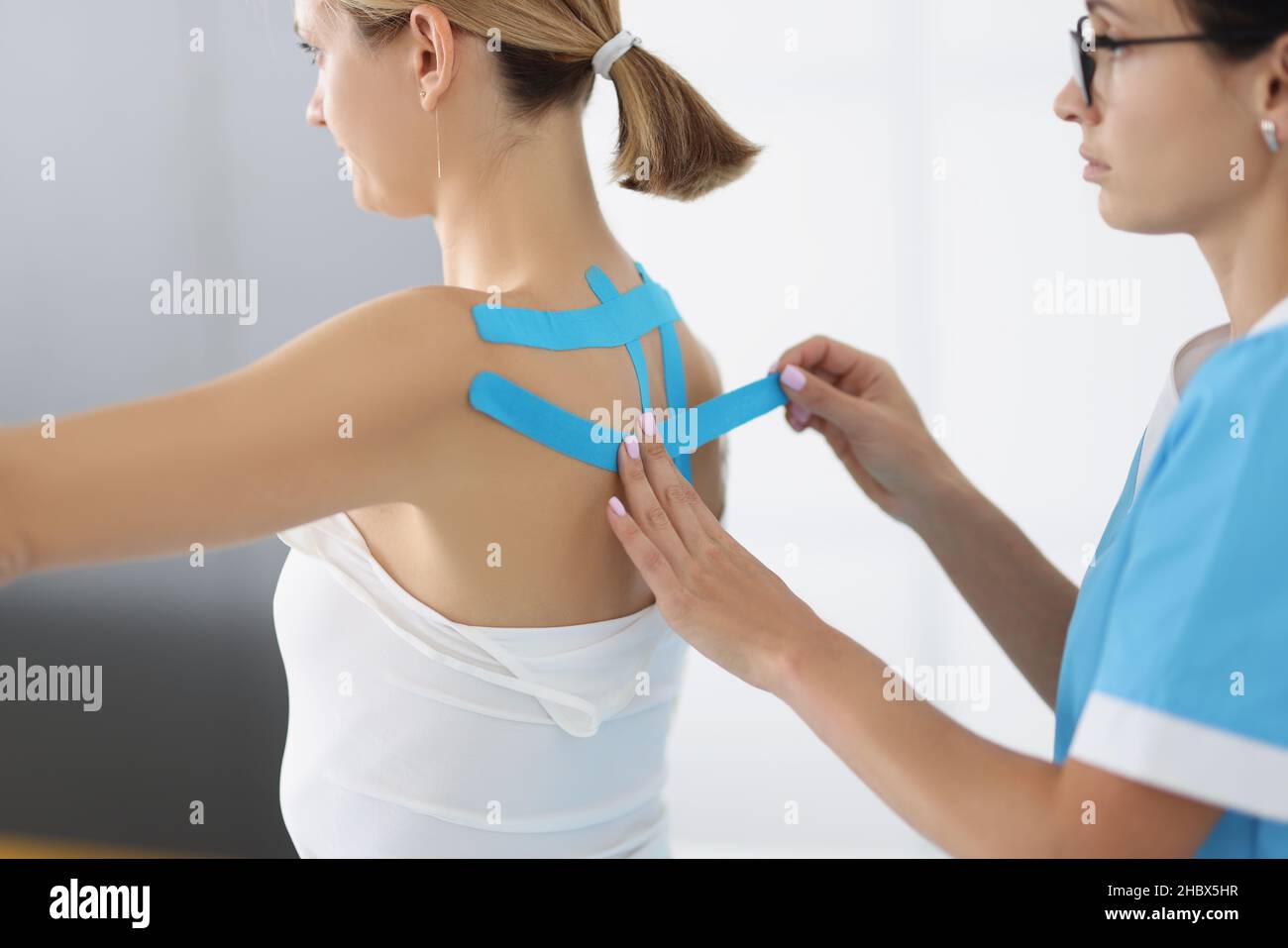 Arzt bringen Sie Kinesiologieband auf den Patienten zurück in der Klinik Stockfoto