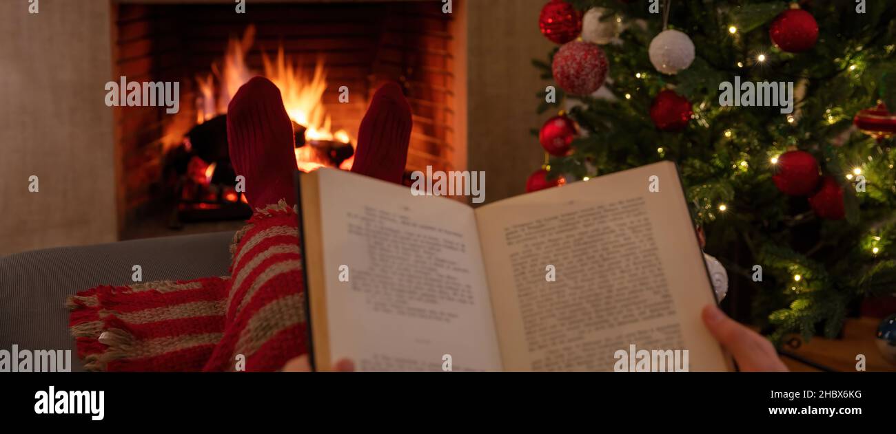 Weihnachten Entspannung zu Hause. Mann mit einem offenen Buch, brennender Kamin Hintergrund. Warmes gemütliches Zuhause, Winterurlaub. Stockfoto