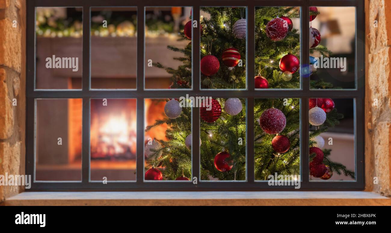 Weihnachtsfenster. Weihnachtsbaum Dekoration, brennender Kamin, Winter Ferienhaus Interieur, Blick von draußen Stockfoto