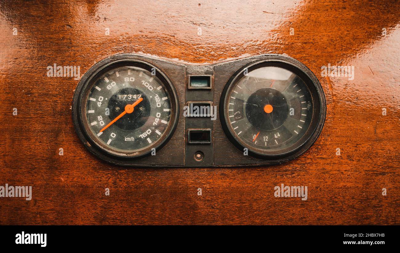 Alter Kilometerzähler und Tachometer in Kilometern pro Stunde auf altem hölzernen Armaturenbrett Stockfoto