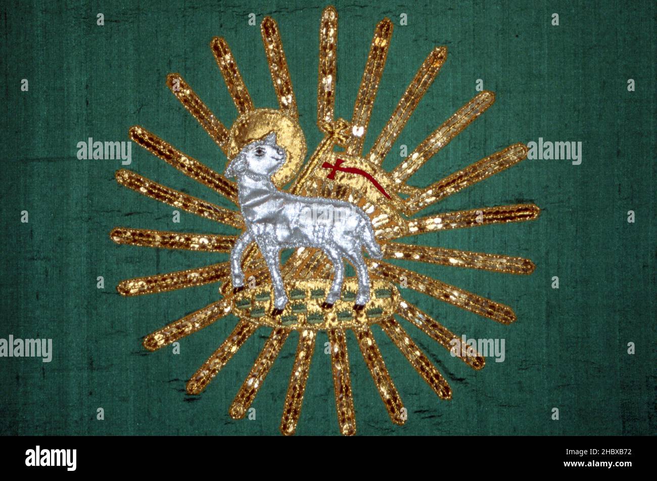 Makelloses Passahlamm mit einem Weihnachtssternenkreuz, Christus, der Erlöser. Glänzendes, besticktes silbernes Lamm mit goldenem Stern auf grünem Hintergrund Stockfoto