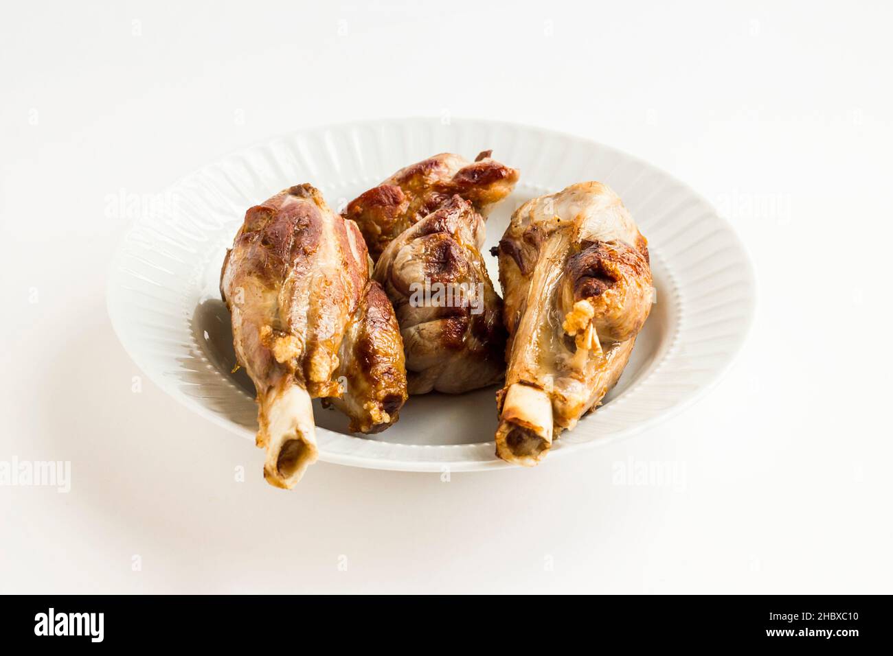 Gut gekocht drei Stücke Lammschenkel in weißen Teller mit frischem Thymian, Union und Knoblauch.The Sacrifice Festival Essen Stockfoto