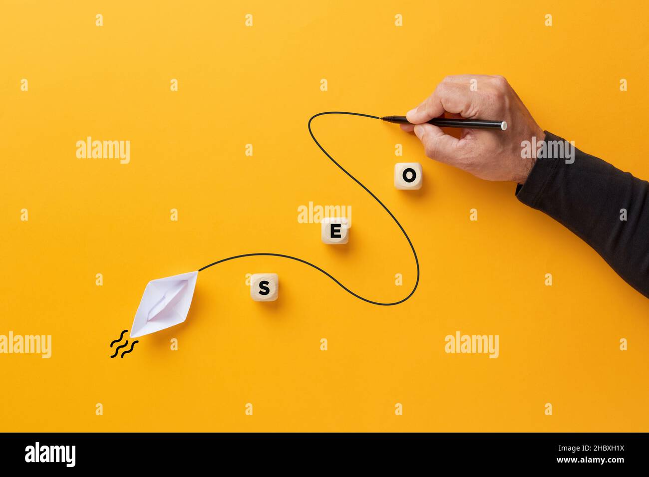 Suchmaschinenoptimierung Internet- oder Web-Traffic-Strategiekonzept. Männliche Hand zeichnet eine geschwungene Linie, die ein Papierboot mit dem Akronym SEO führt. Stockfoto
