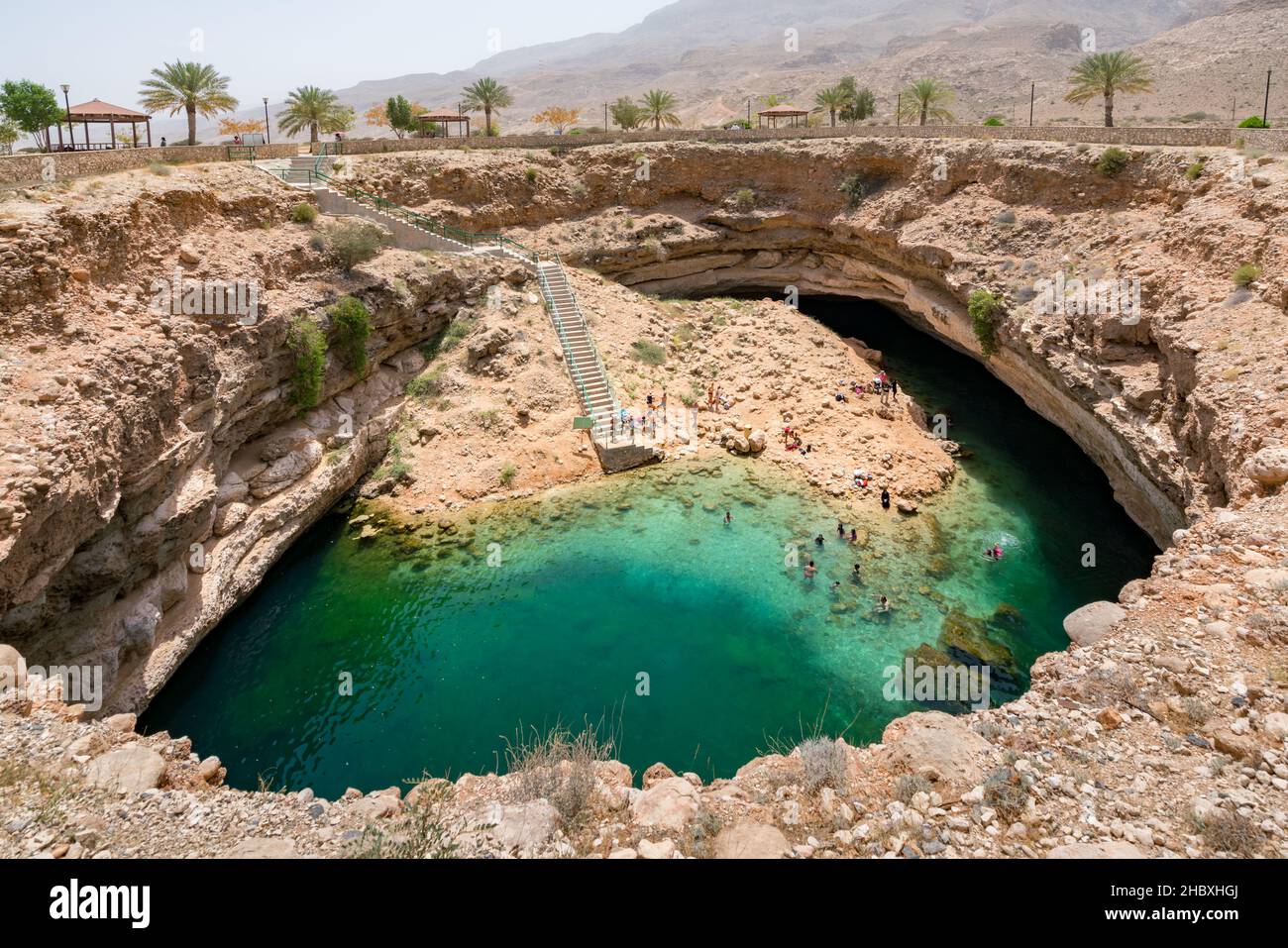 Bimmah, Oman - 04.05.2018: Menschen schwimmen und hängen im türkisfarbenen Wasser des Bimmah Sinkhole Pools oder Hawiyyat Najm, der Meereslagune in Omanian Stockfoto