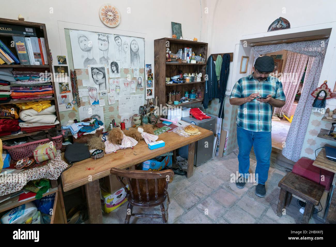 Kerman, Iran - 04.11.2019: Der iranische Künstler steht in seinem Laden neben seinem Schreibtisch. Stockfoto