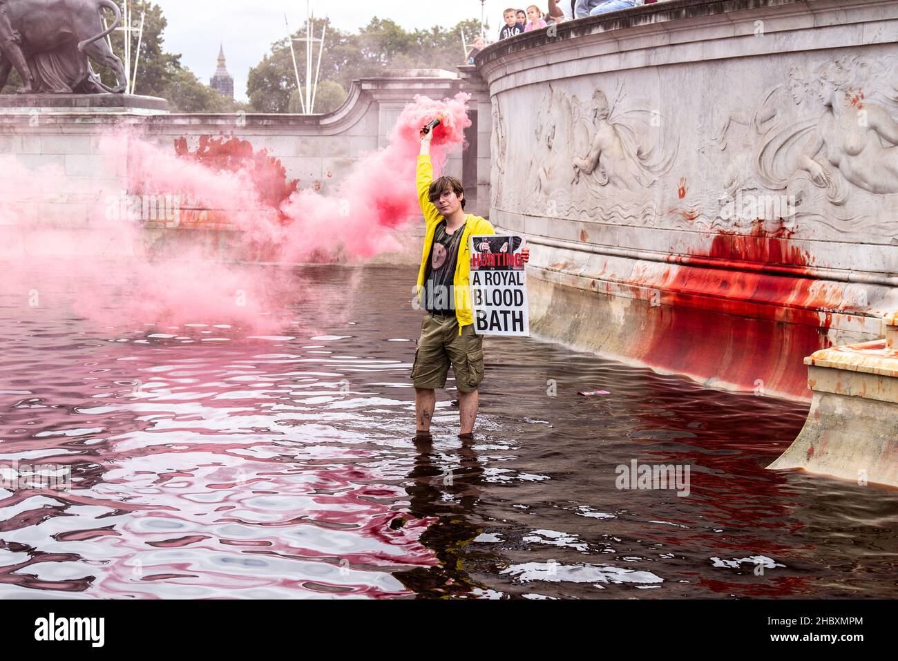 Die Rebellion der Tiere färbt den königlichen Brunnen rot, und der Aktivist hält ein Schild mit der Aufschrift „königliches Blutbad“ und hat ein rosa Flare: Buckingham Palace 2021 Stockfoto