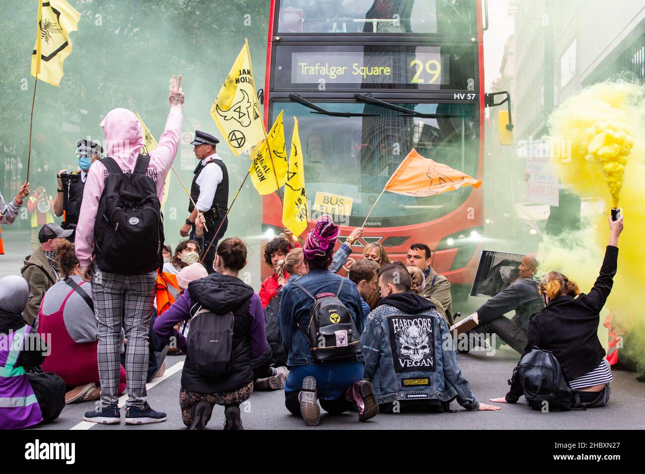 Tieraufständler sitzen im Straßenblockbus mit gelbem Flare und Flaggen London 2020 Stockfoto