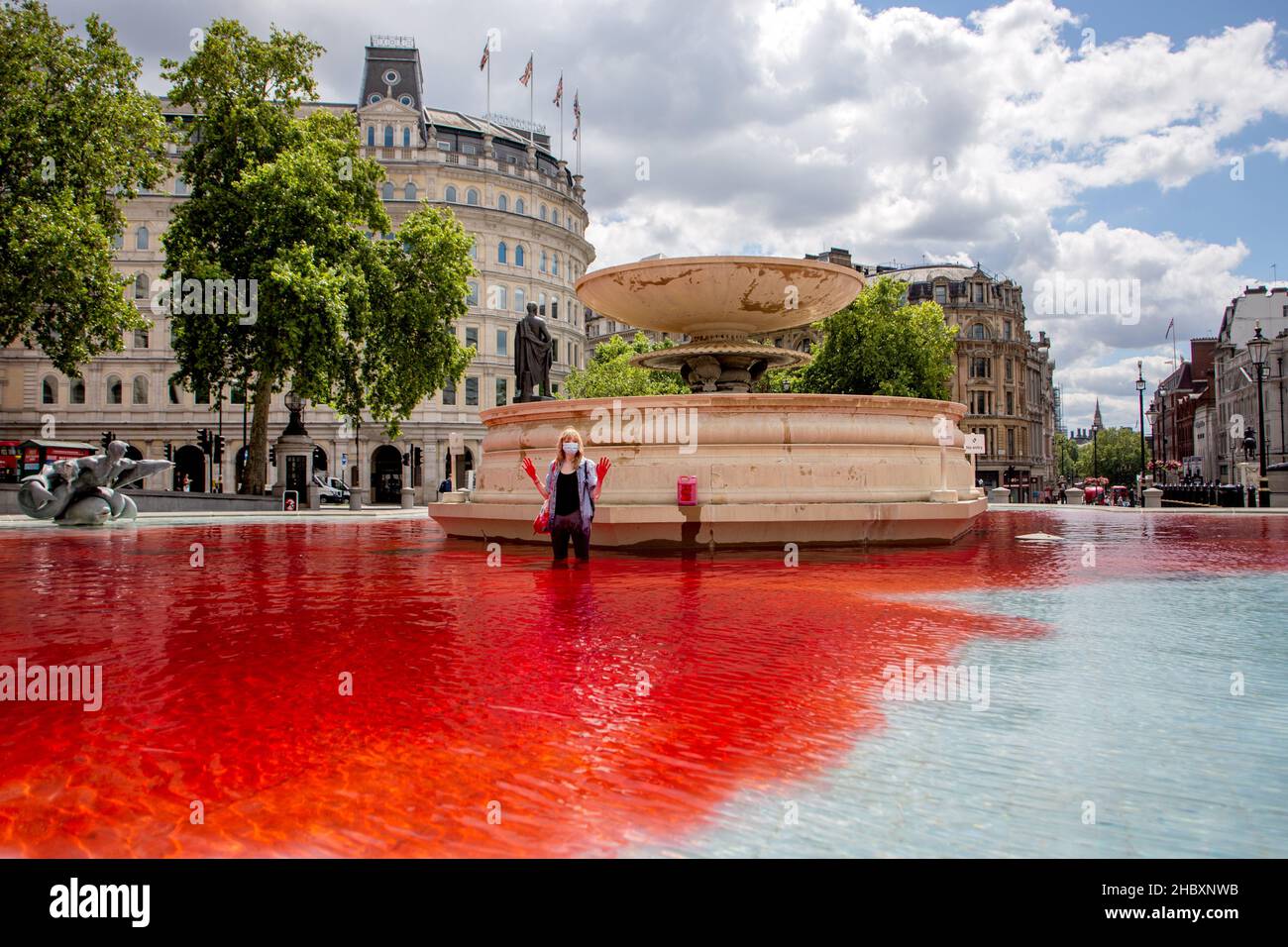 Tierischer Rebellion-Aktivist, der im roten Wasser im Trafalgar Square-Brunnen steht und Hände in der Luft hält London 2020 Stockfoto