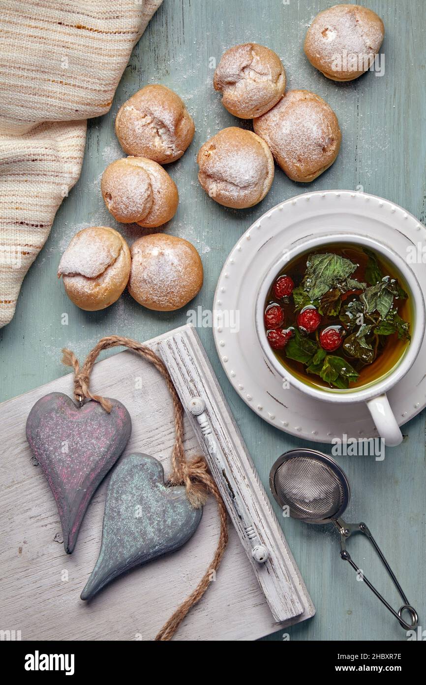 Köstliche Profiterolen mit Schlagsahne und zwei dekorativen Holzherzen Stockfoto