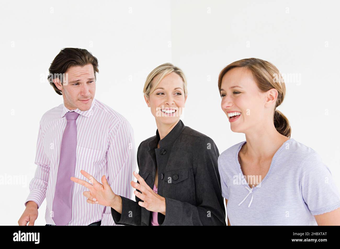 Zwei Frauen und ein Mann in professioneller Kleidung reden und lächeln. Stockfoto