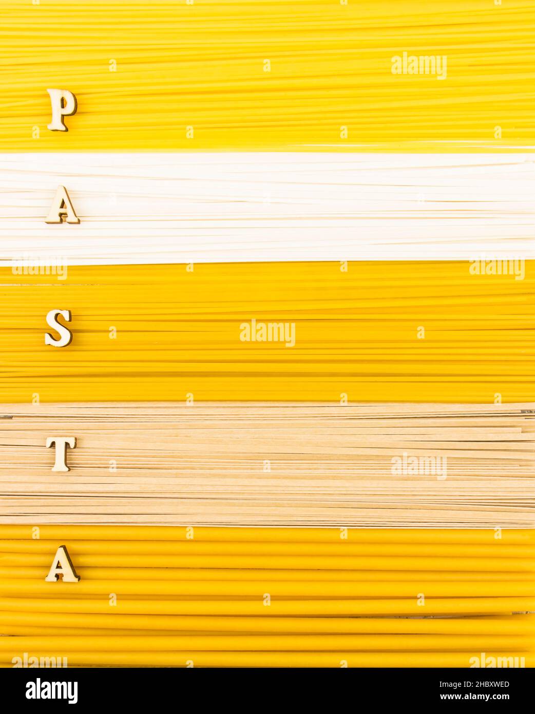 Ein Hintergrund von trockenen langen Nudeln, Nudeln und Spaghetti mit einem Wort aus Holz Buchstaben -Pasta. Draufsicht. Flach legen Stockfoto