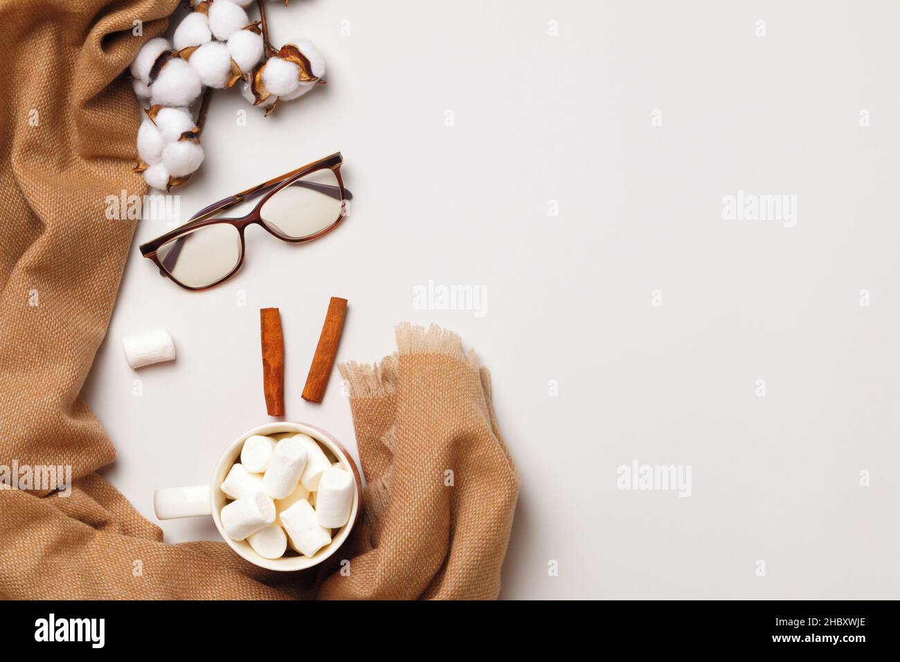 Beige Kaschmir Schal Tasse marshallows Zimt Zweig der Baumwollgläser auf einem grauen Hintergrund. Das Konzept von Winterkomfort und Gemütlichkeit. Flach auflegen Stockfoto