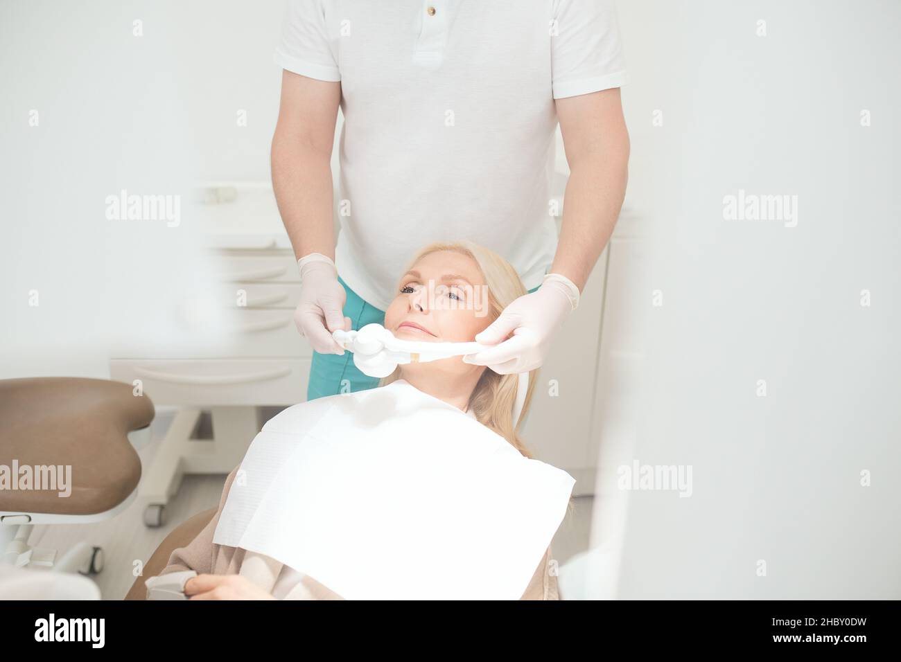 Ein männlicher Zahnarzt, der seinen Patienten auf die Zahnoperation vorbereitet Stockfoto