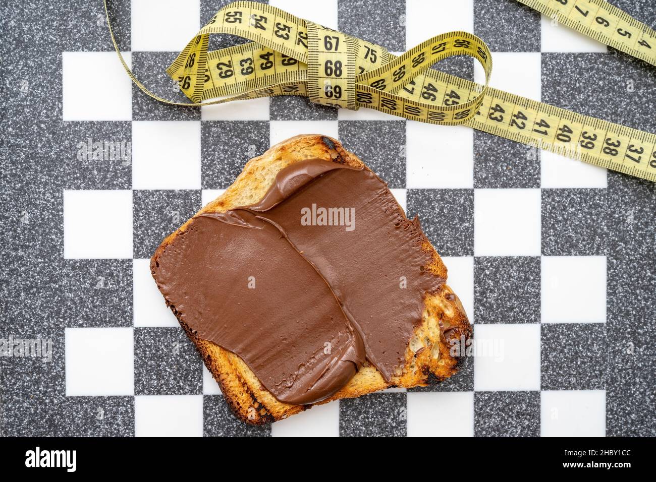 Schokolade auf Toast mit einer Schleife aus Maßband, auf einem Schachbrett Stockfoto