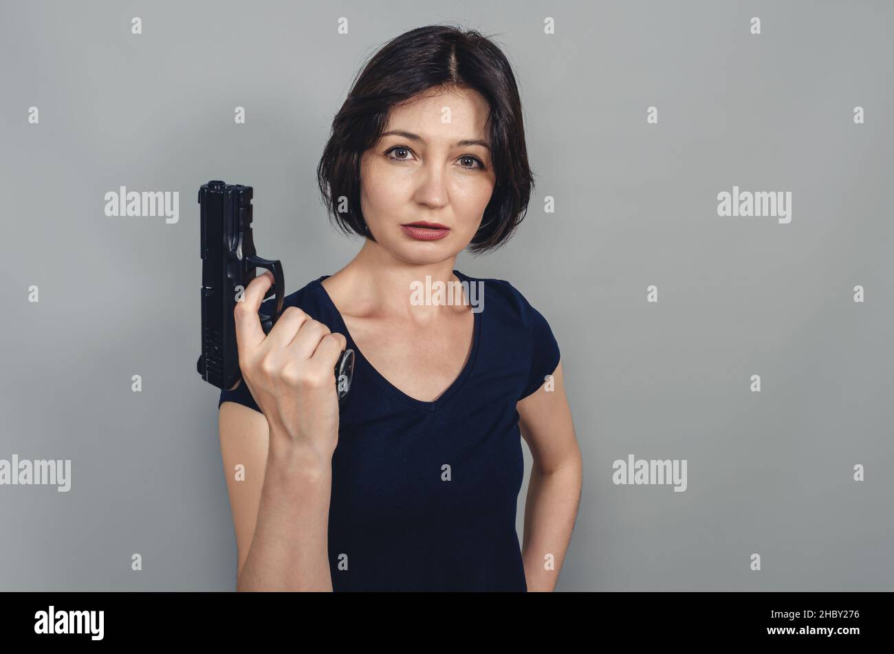 Pistole in den Händen der Frau. Kurze schwarze Haare. Konzept der Gewalt. Stockfoto
