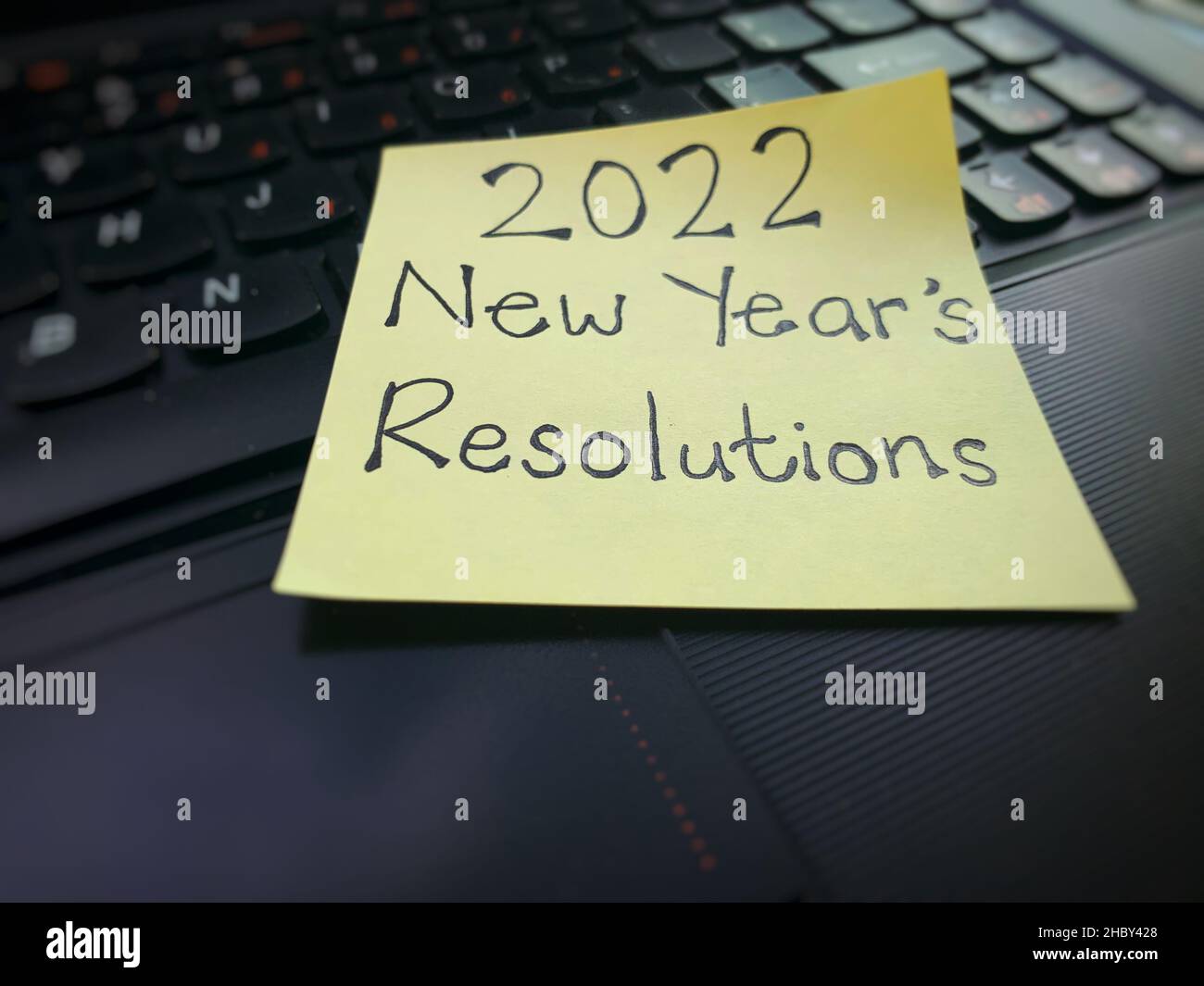 Auflösungstext für das Jahr 2022 auf einem schwarzen Laptop auf einem Haftnotiz geschrieben. Stockfoto
