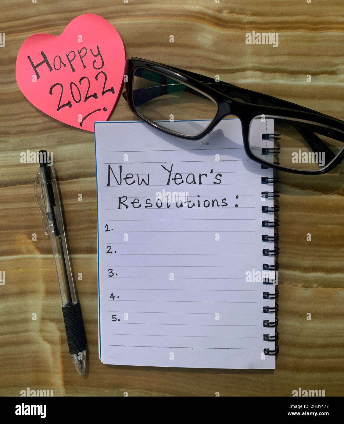 Auflösung für das neue Jahr 2022 mit Stift, Haftnotiz und Brillenhintergrund. Stockfoto