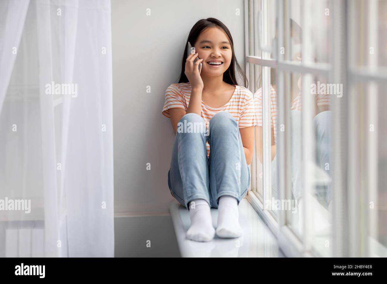 Ziemlich asiatische schulpflichige Mädchen mit Telefongespräch zu Hause Stockfoto
